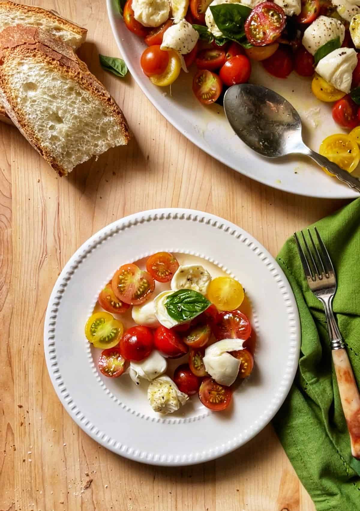 A caprese salad made with cherry tomatoes on a white plate.