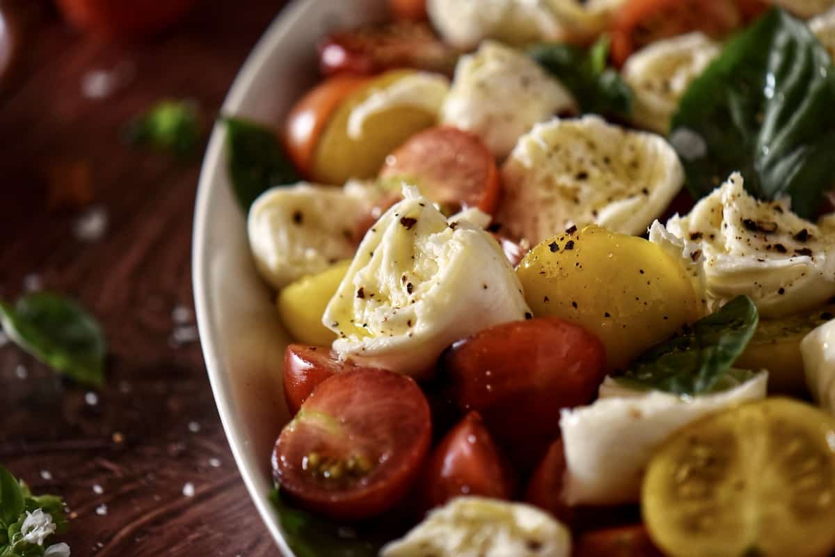 A close up photo of a caprese salad with cherry tomatoes.