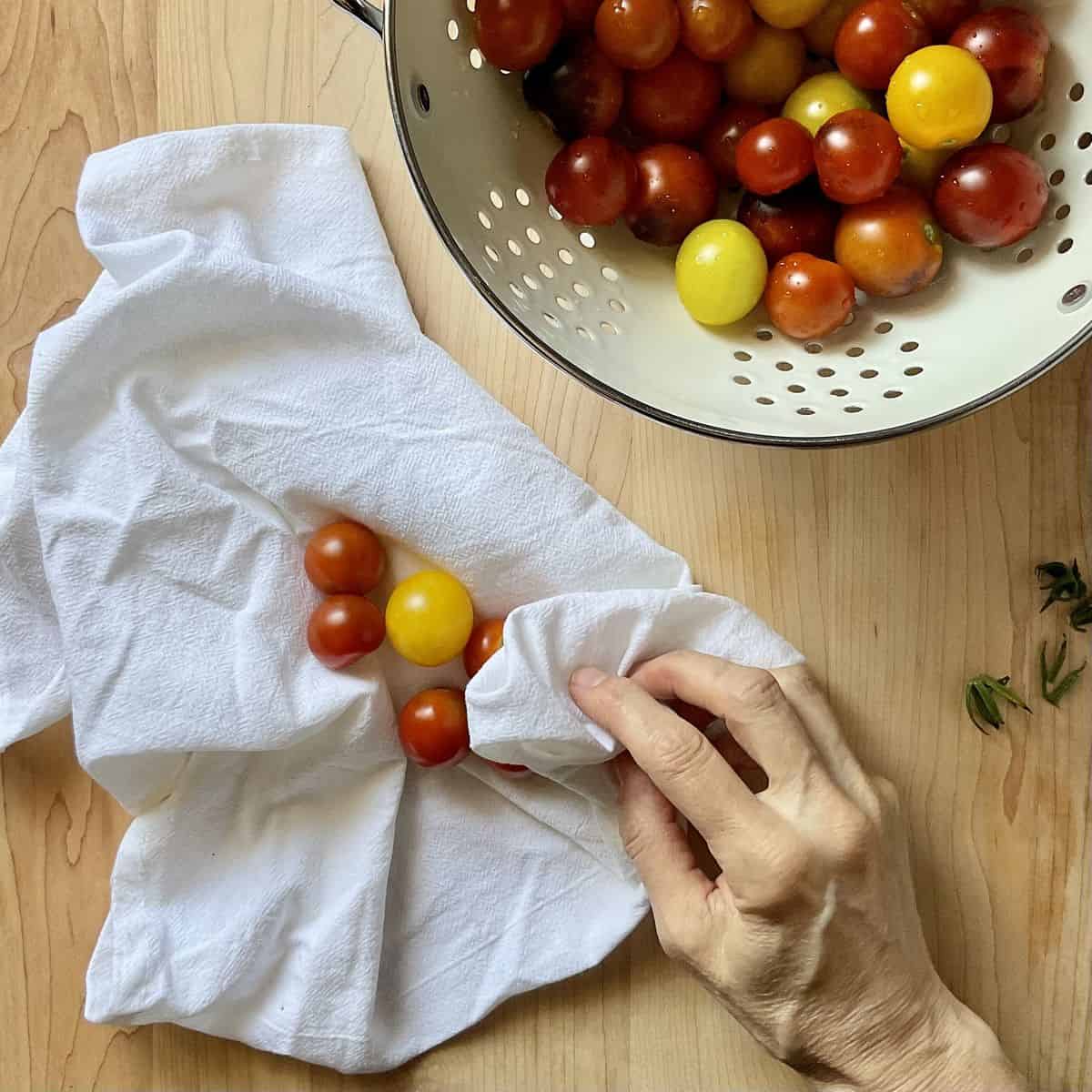 Cherry tomatoes in the process of being fried with a tea towel.