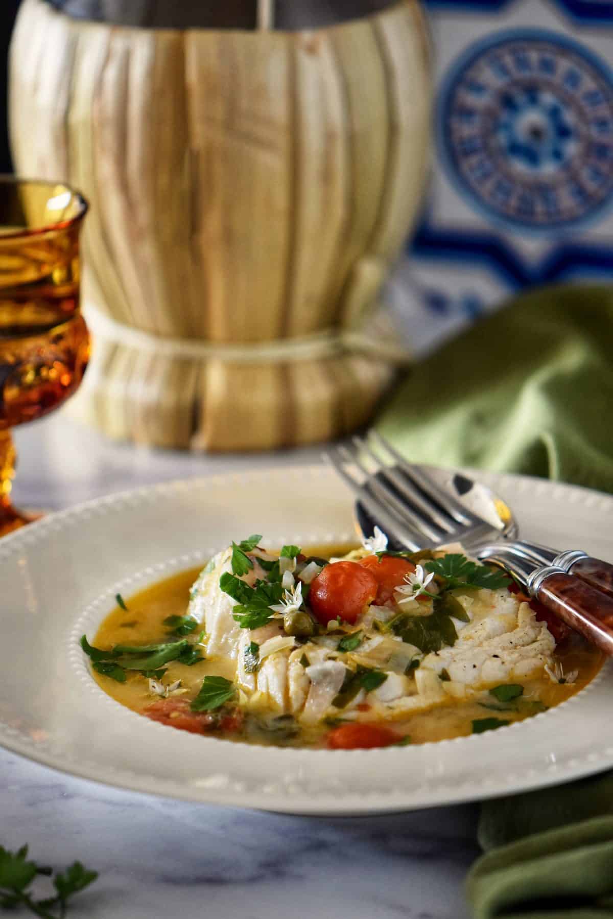 Poached Italian cod fish in a white dish.