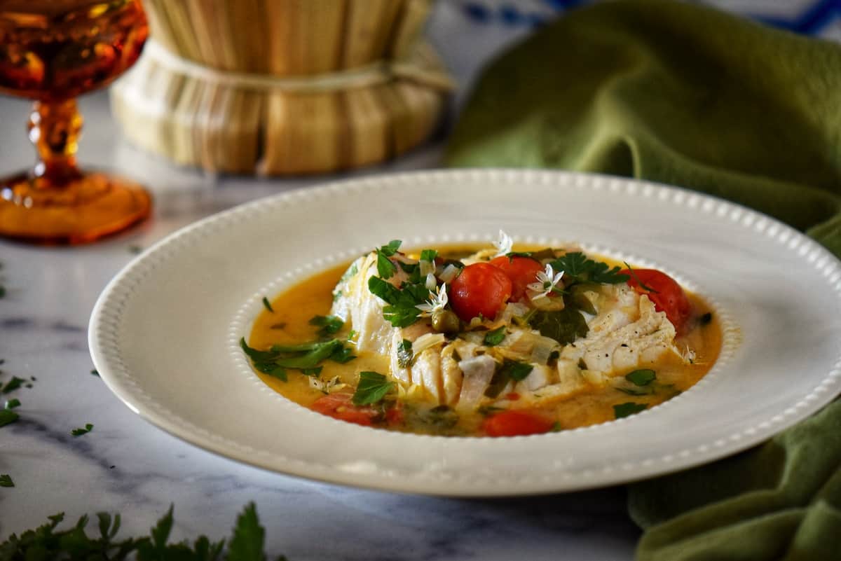 Poached Italian cod fish in a white dish.