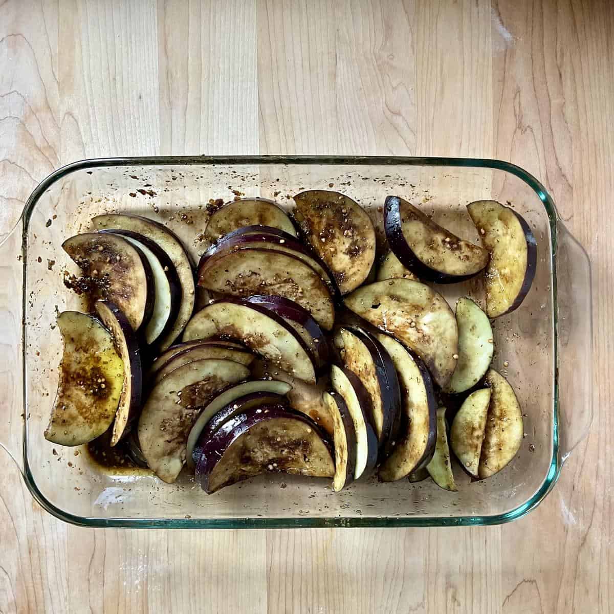 Marinating sliced eggplant in a shallow dish.