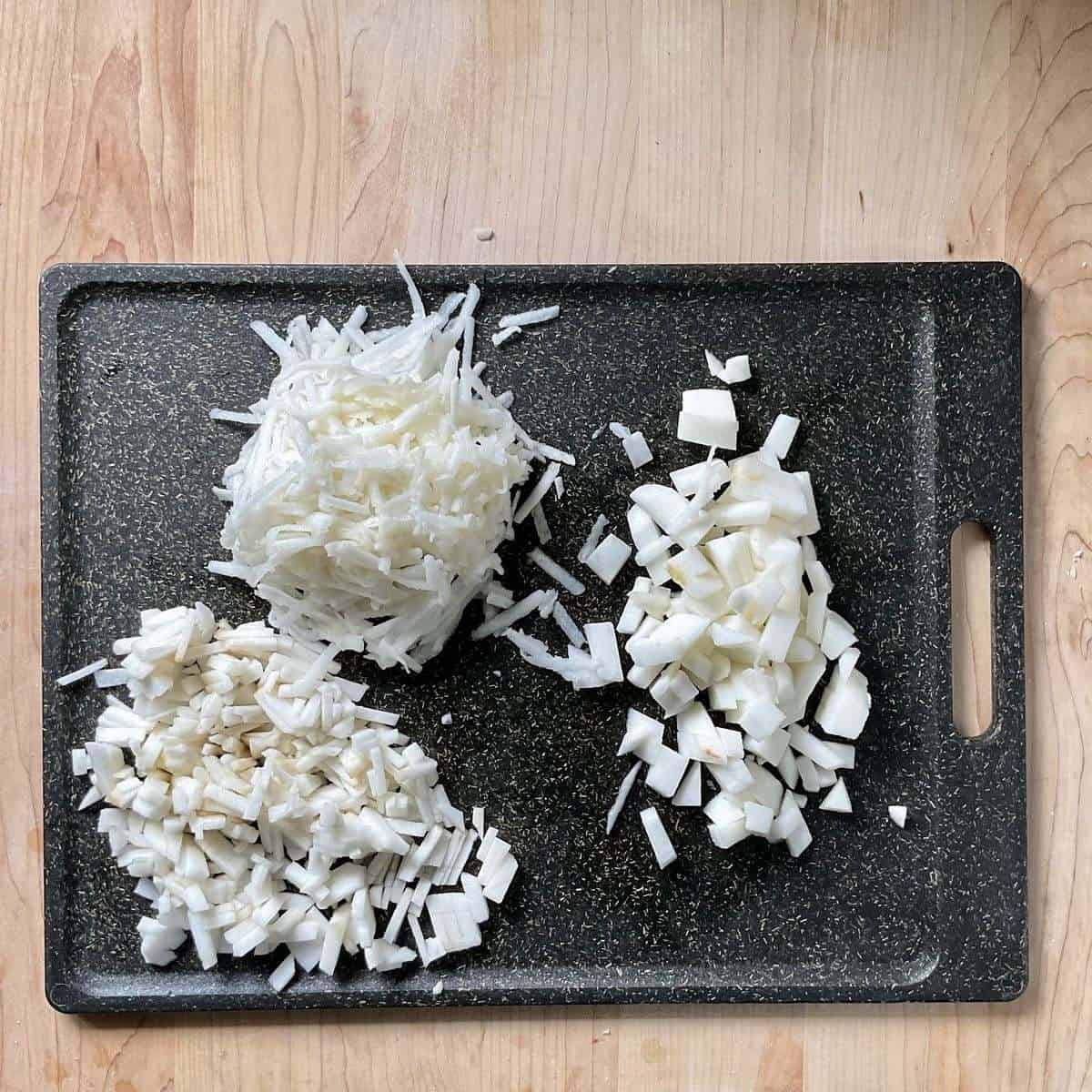 Chopped and grated apples on a cutting board.