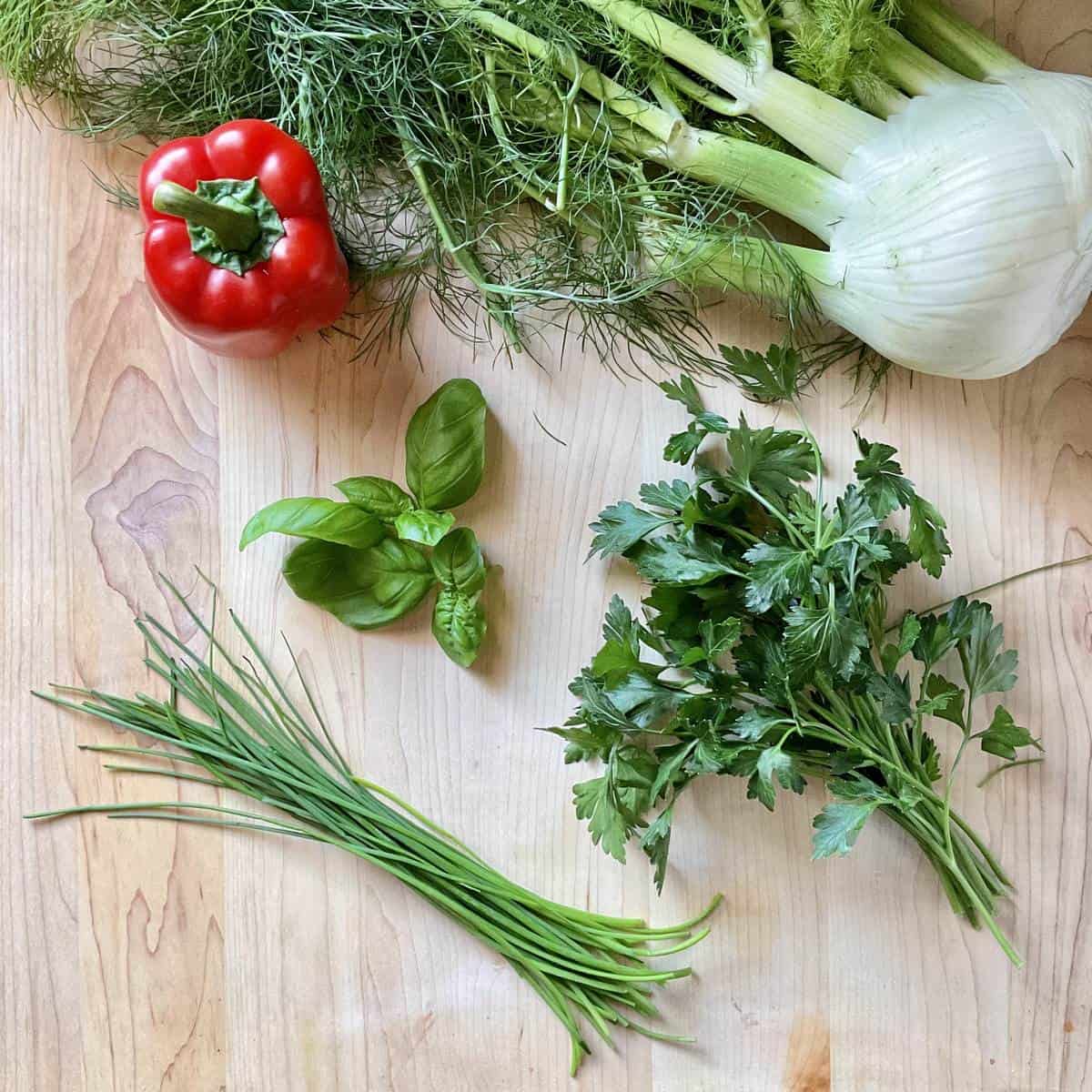 Ingredients to make fregola salad on a wooden board.