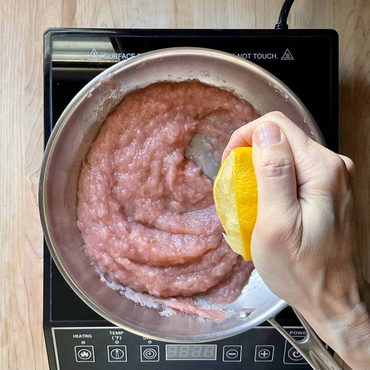 Lemon juice being added to apple butter in a pan.