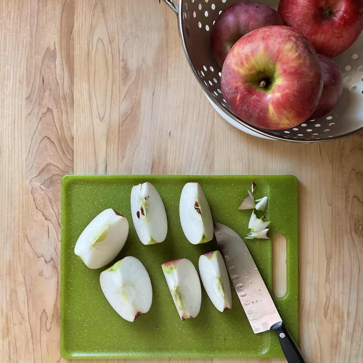 Chopped apples next to a colander of washed apples.