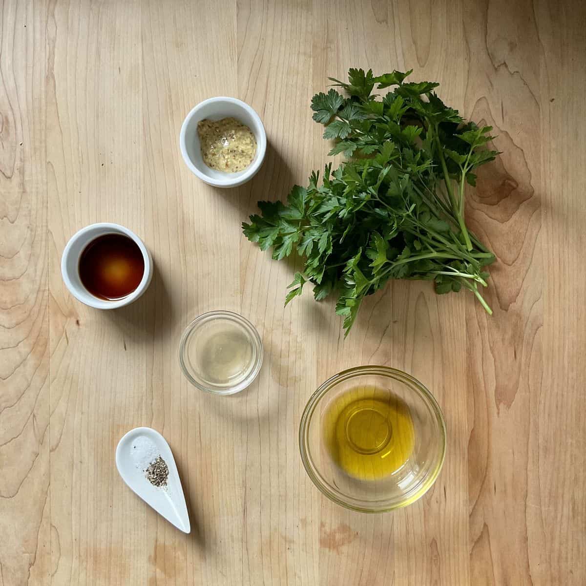Ingredients to make a balsamic vinaigrette on a wooden surface.