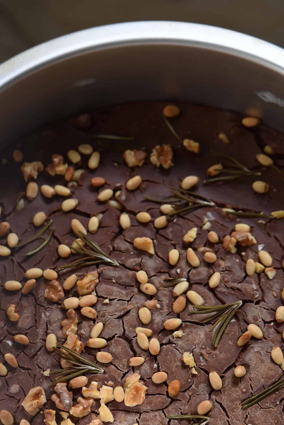 Pine nuts and walnuts on the surface of an Italian cake.