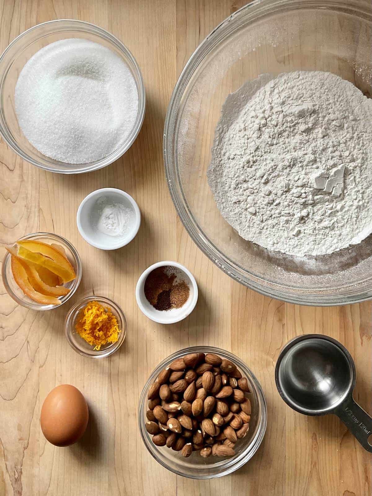 Ingredients to make Roccocò cookies on a wooden board.