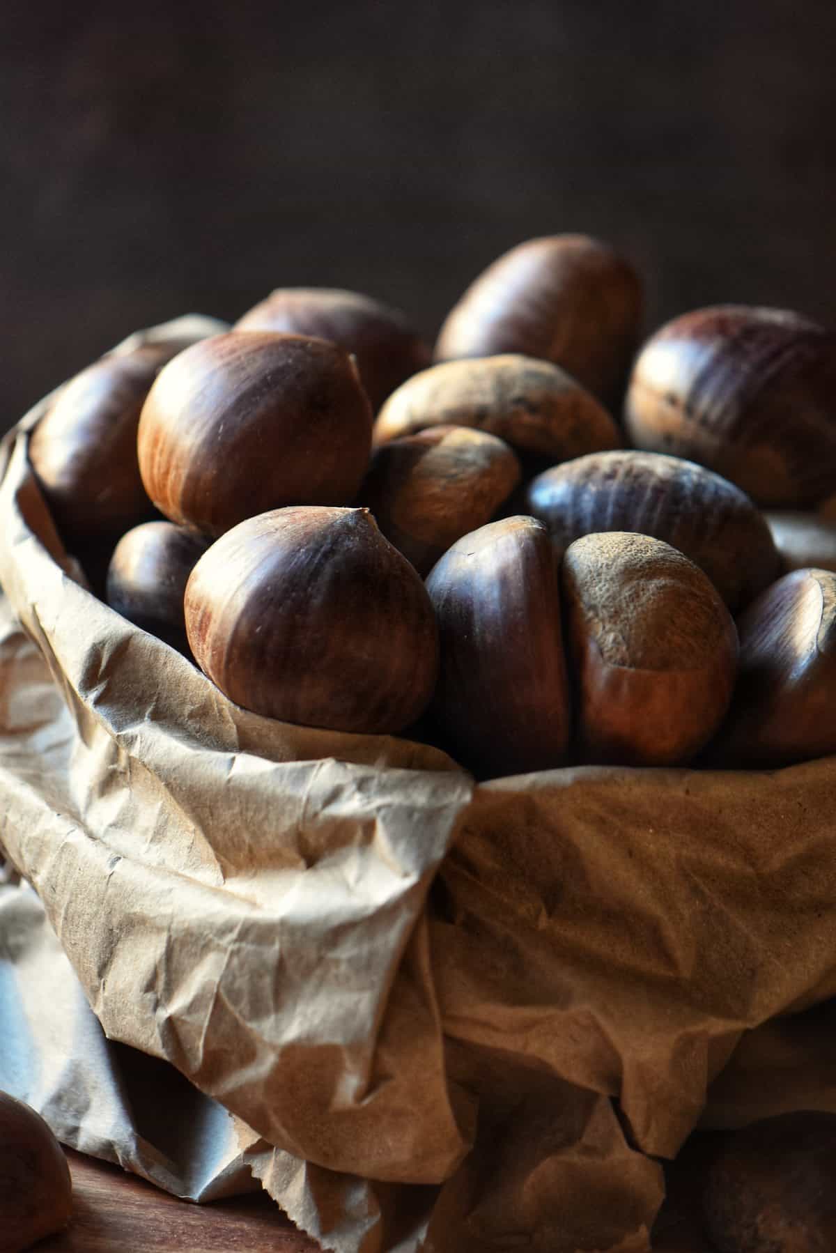 Large, golden brown chestnuts in a paper bag.