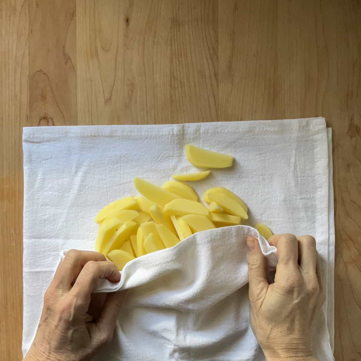 Sliced potatoes on a white tea towel.