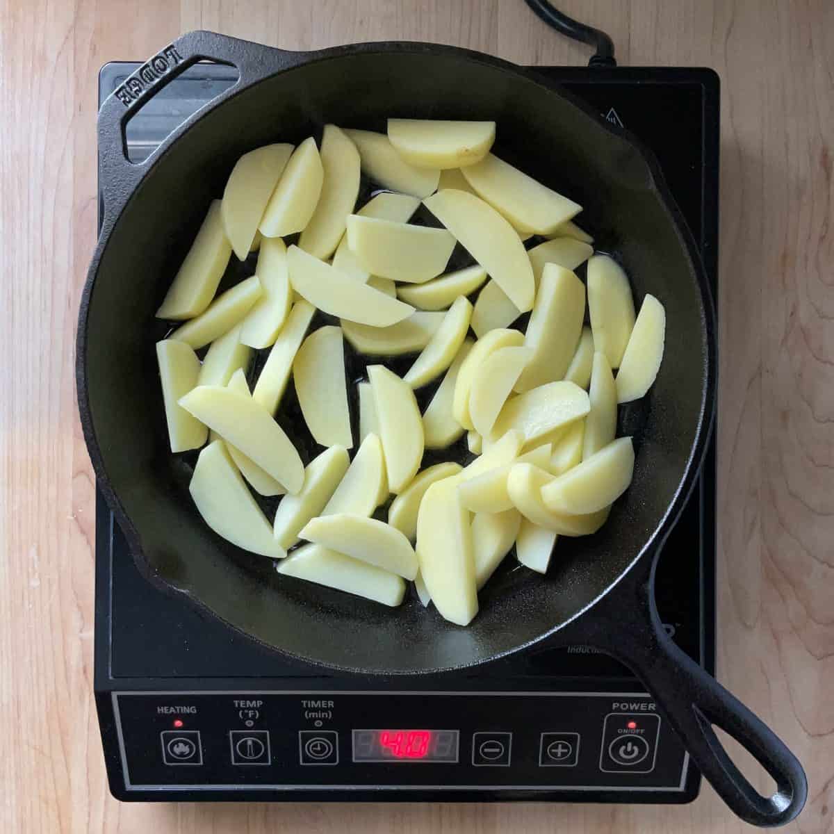 Sliced potatoes in a cast iron pan.
