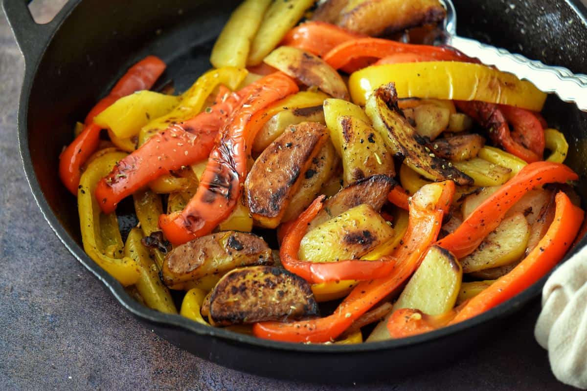 Italian peppers and potatoes in a cast iron pan.