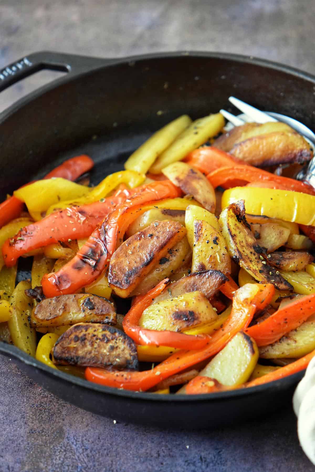 Italian peppers and potatoes in a cast iron pan.