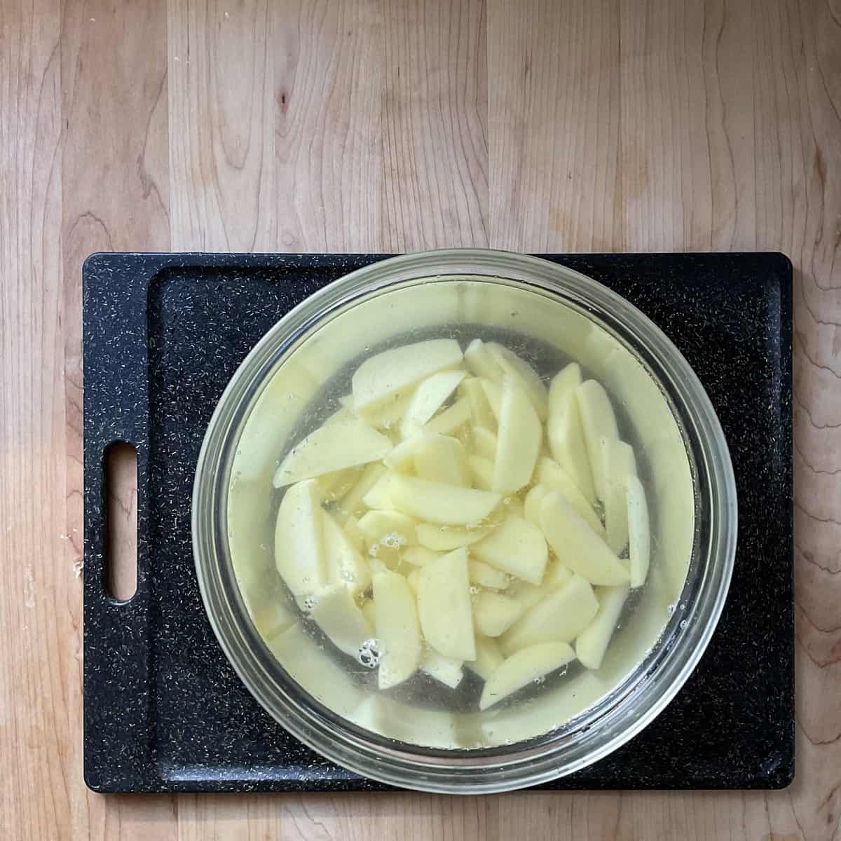 Sliced potatoes in a bowl of water.