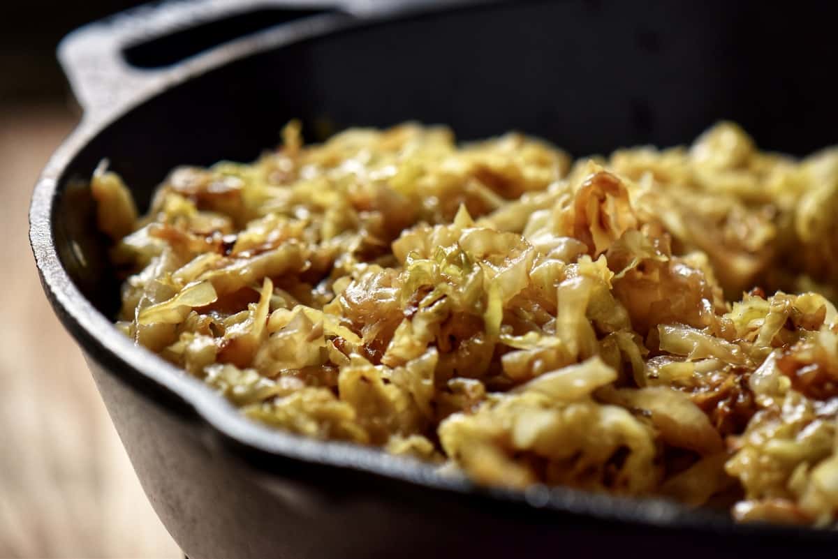 A close up photo of caramelized cabbage and onions in a cast iron pan.