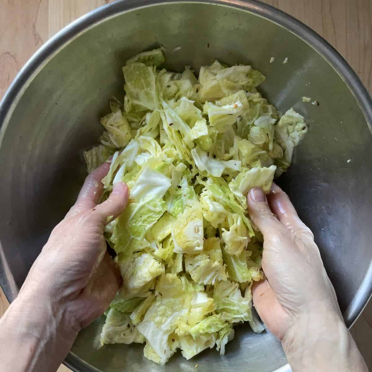 Chopped cabbage being tossed in a large bowl.