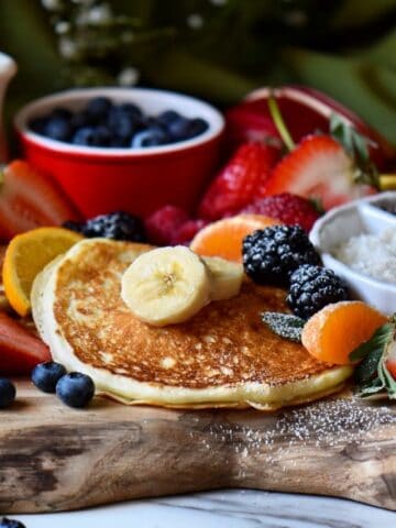 Buttermilk pancakes and fruit on a wooden board.