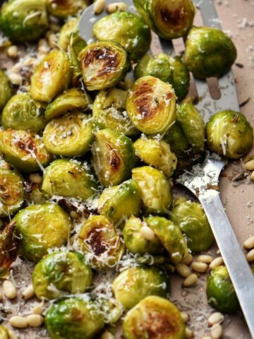 Roasted Brussels sprouts on a platter, with grated Parmesan cheese grated over the top.