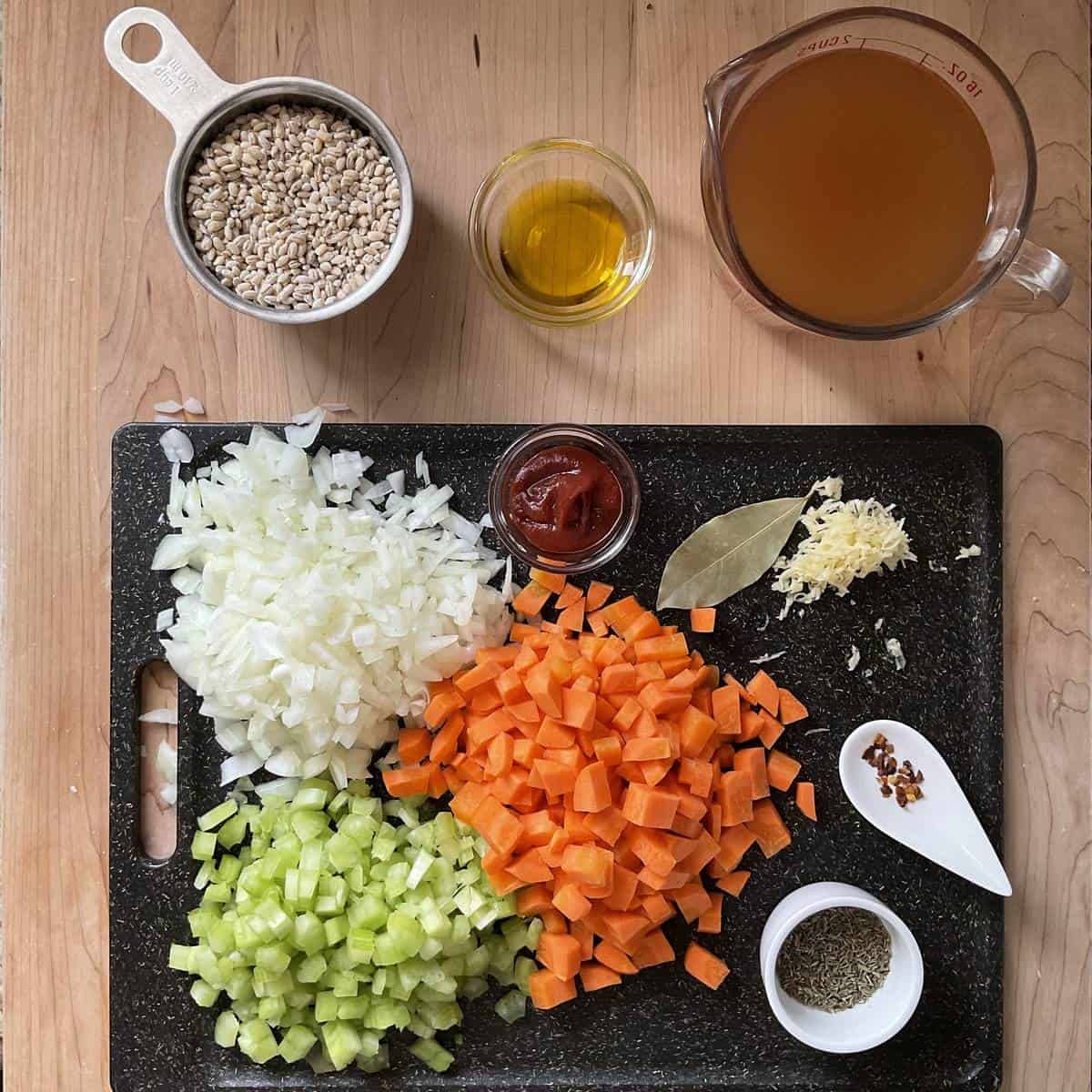 Chopped vegetables and ingredients to make a homemade soup on a cutting board.