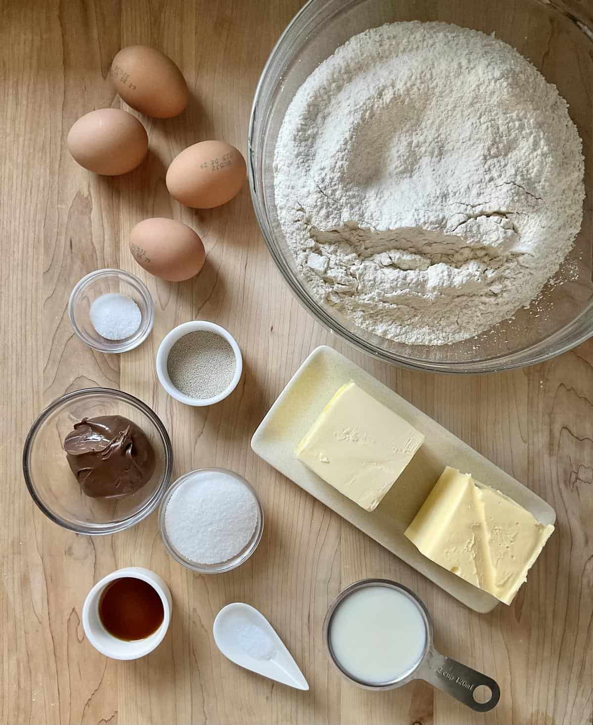 Ingredients to make crescent-shaped chocolate-filled cookies on a wooden board.