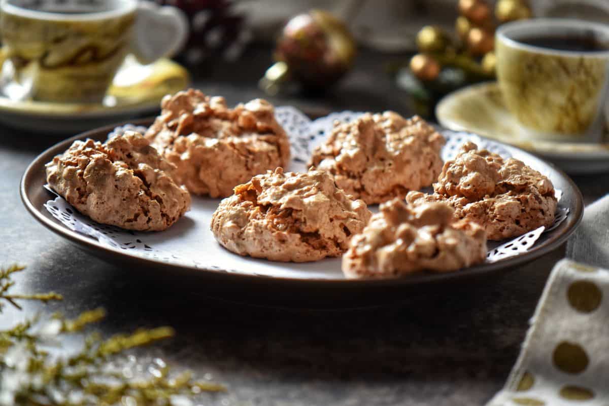 A tray of brutti ma buoni cookies on a table surrounded by Christmas decor.