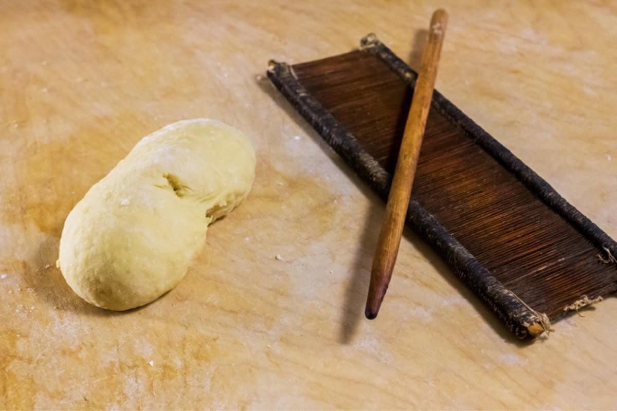 A ball of dough and an original board and rod, called "petene" and "fuso" to make caragnoli.