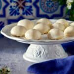 Lemon glazed ricotta cheese cookies on a white cake platter.