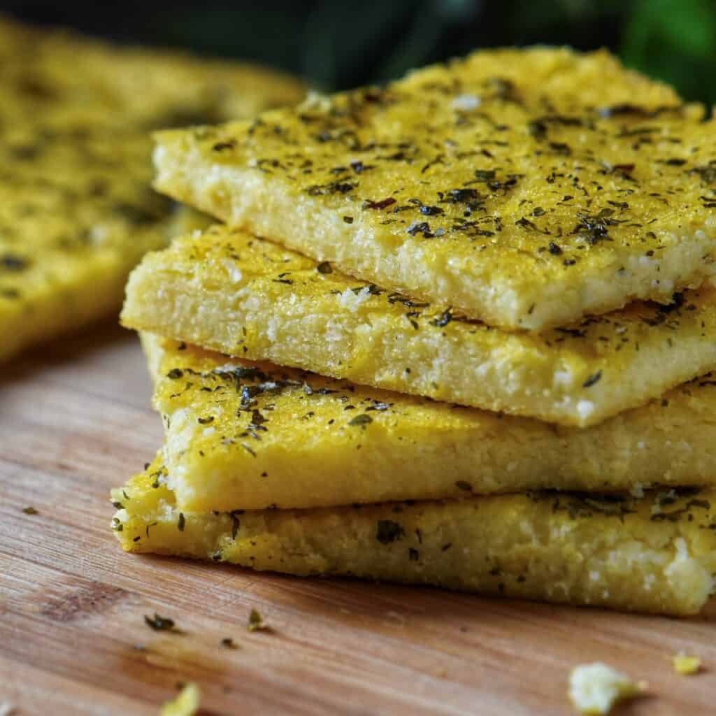 Slices of Polenta Pizza cut into sticks, served on a wooden board.