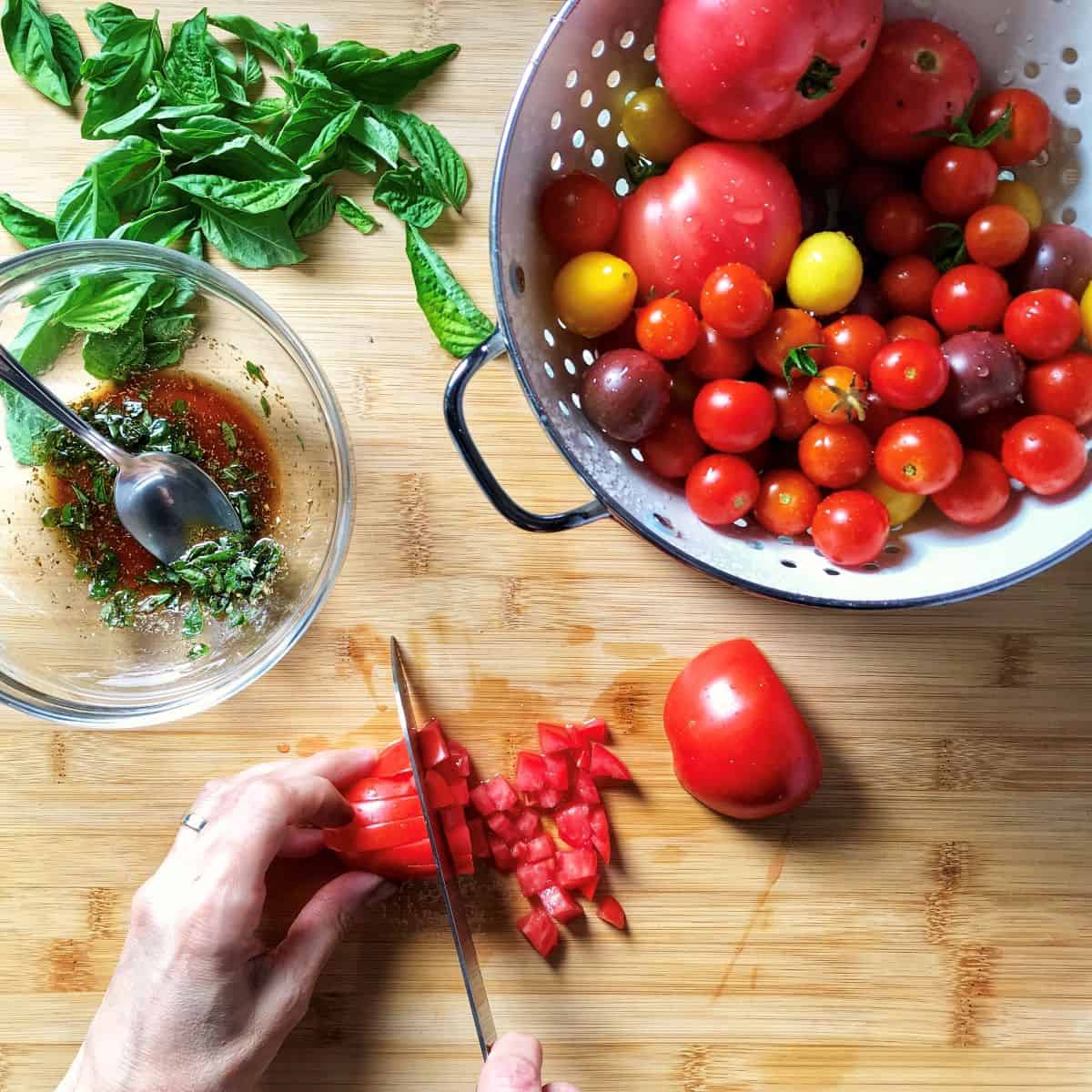 Tomatoes are being diced on a wooden board.