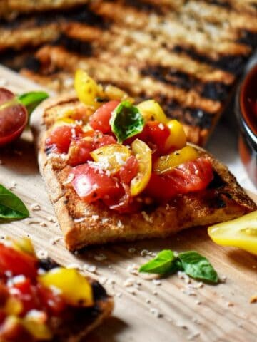 Slices of tomato basil bruschetta on a wooden board, ready to be served as an appetizer.
