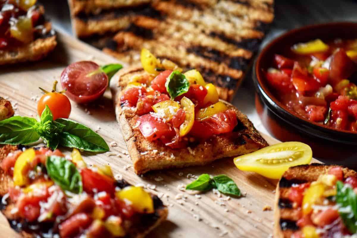 Slices of tomato basil bruschetta on a wooden board, ready to be served as an appetizer.