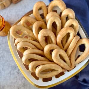 Anise taralli in a basket next to a blue tea towel.