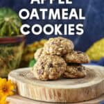 Apple oatmeal cookies stacked on a wooden platter, showing cranberries and pecans throughout