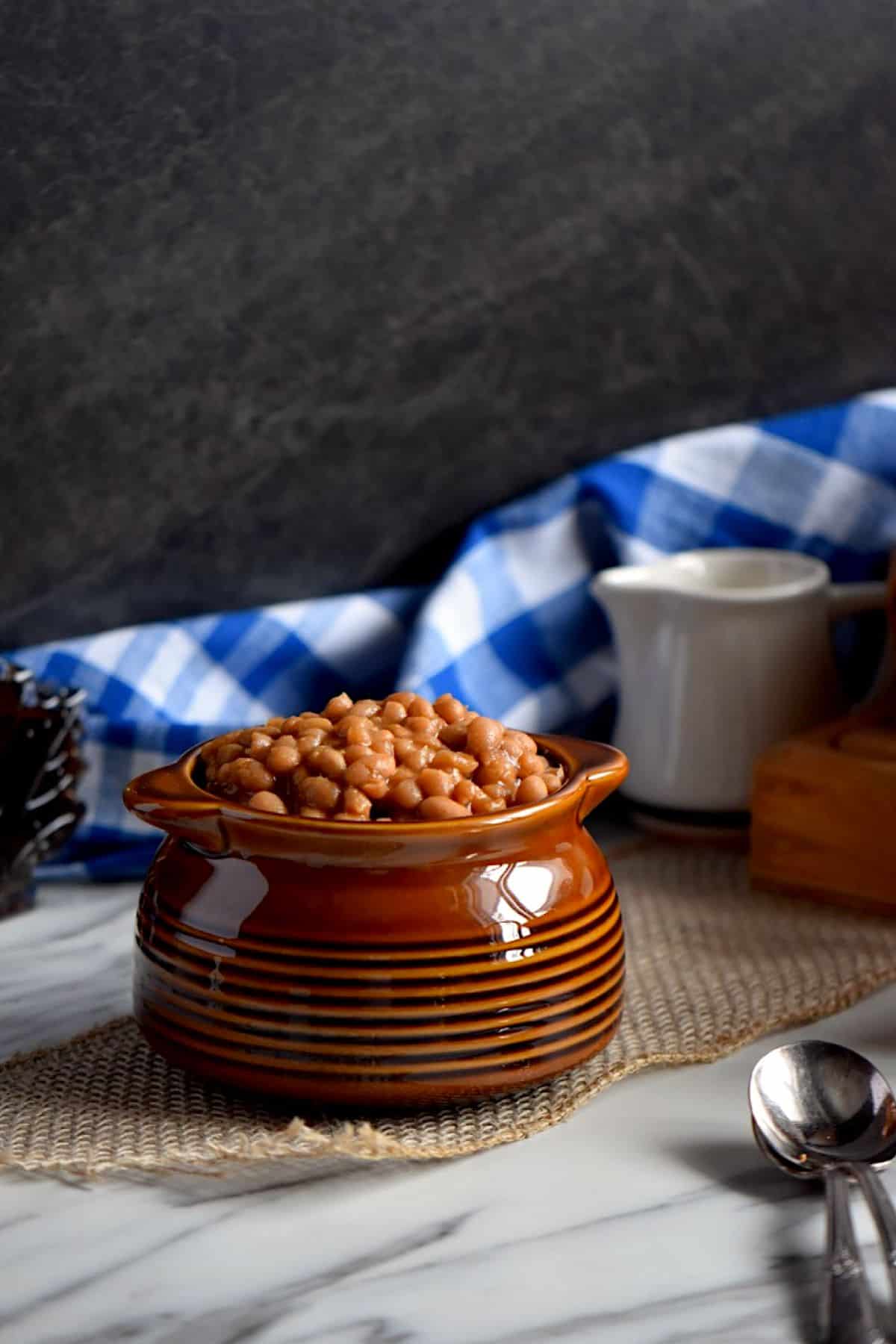 Homemade baked beans in a brown ceramic pot.