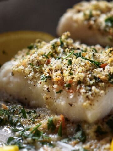 Oven baked cod fish garnished with oregano, parsley and homemade breadcrumbs.
