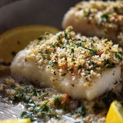 Oven baked cod fish garnished with oregano, parsley and homemade breadcrumbs.