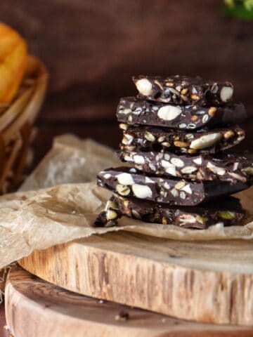 Chocolate bark with almonds and seeds on parchment paper.