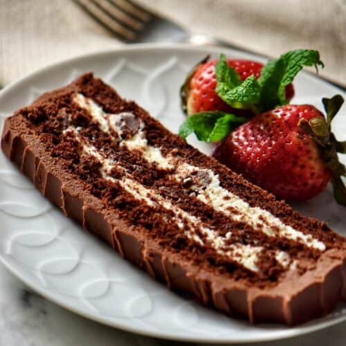 A slice of layered Chocolate Cake with ricotta cheese filling with strawberries on a white plate.
