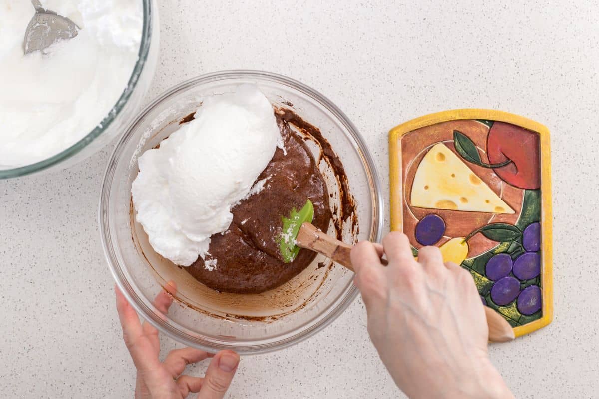 The whipped egg whites are being folded in the chocolate batter.