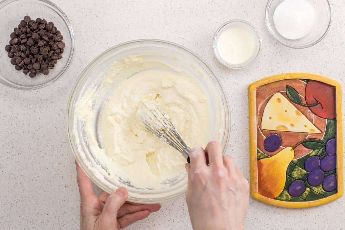 An overhead shot of a bowl of whipped ricotta next to a bowl of chocolate chips.