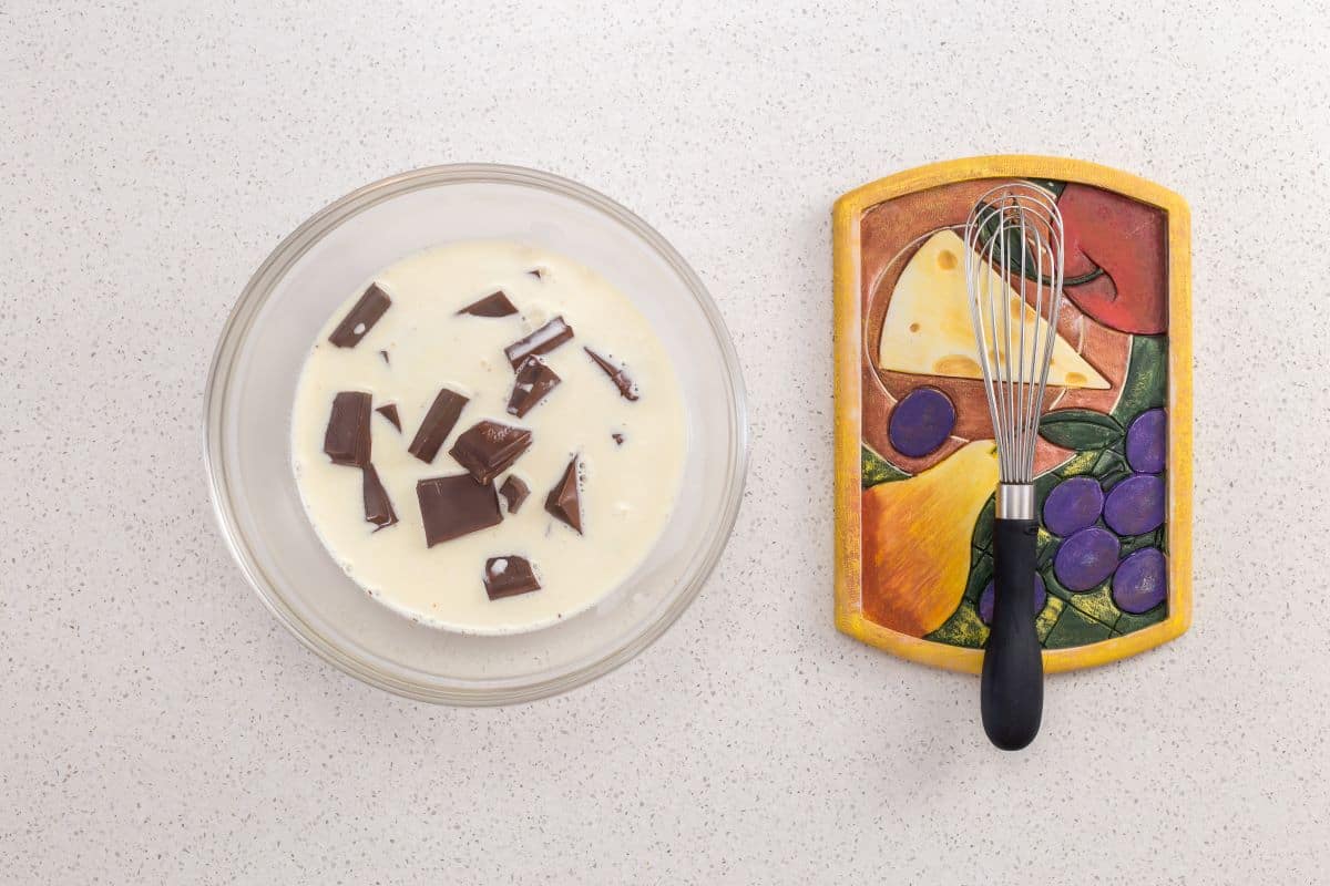 Whipping cream and pieces of chocolate about to be whisked together to make the chocolate ganache frosting.