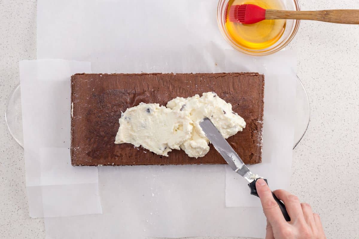 The whipped ricotta filling is being spread over the chocolate layers.