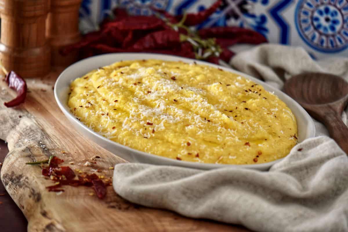 A platter of Italian polenta in a white dish surrounded by chili peppers.