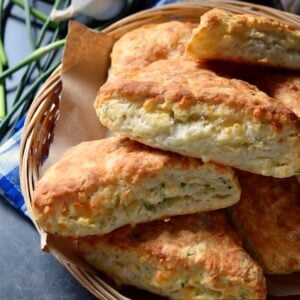 A wicker basket of Cheese Biscuits set over a checkered blue tea towel.