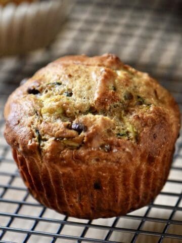 A chocolate chip zucchini muffin on a cooling rack.