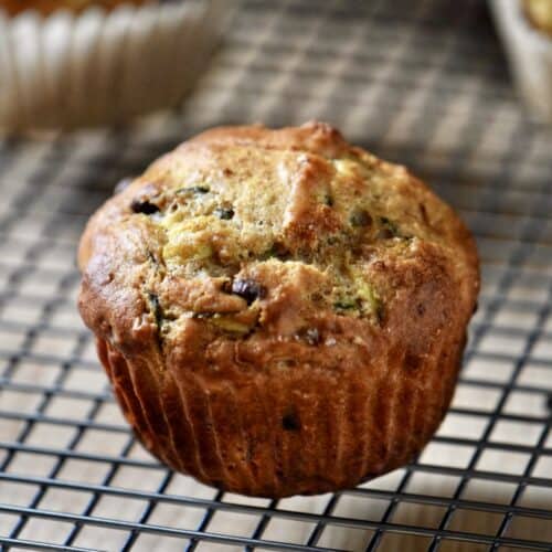 A chocolate chip zucchini muffin on a cooling rack.