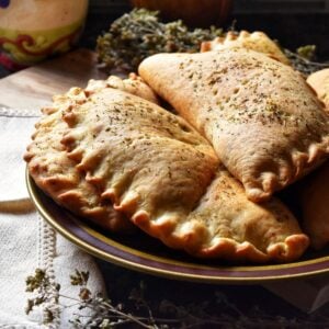 A pile of calzones on a plate.