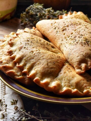 A pile of calzones on a plate.