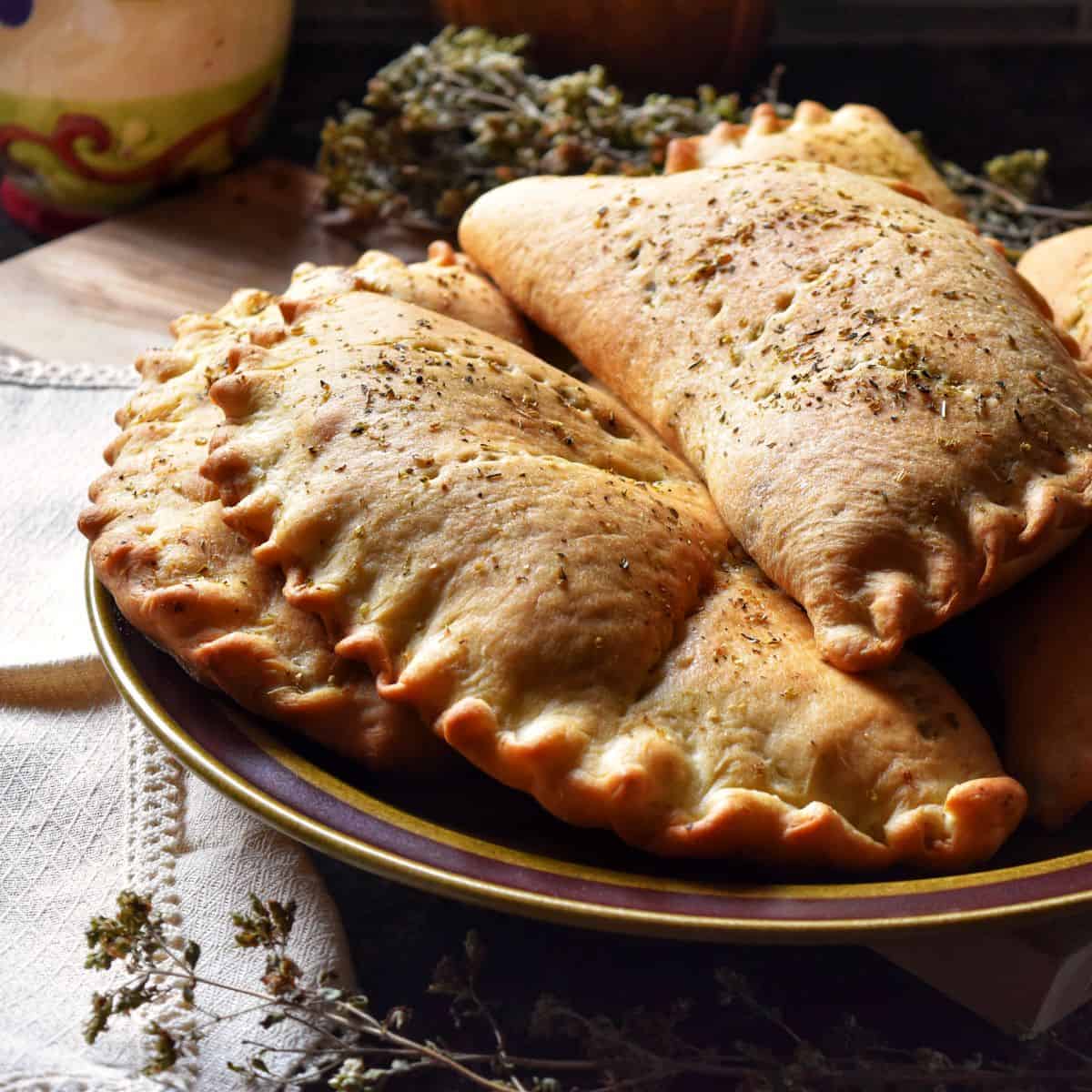 A pile of calzones on a plate. 